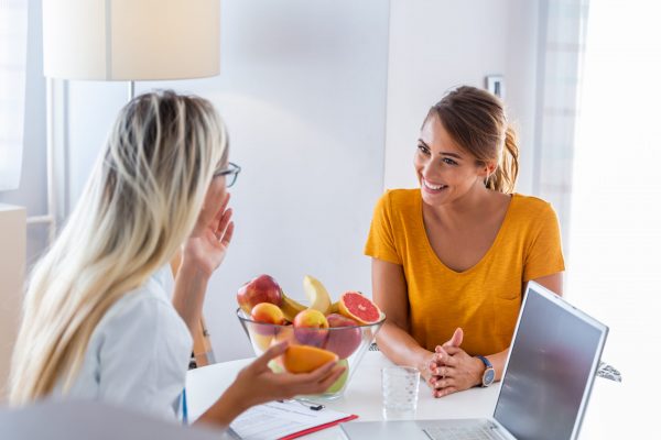 stock-photo-portrait-of-young-smiling-female-nutritionist-in-the-consultation-room-making-diet-plan-young-1570911265